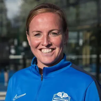 Ang smiling at camera with hair tied back and wearing blue top