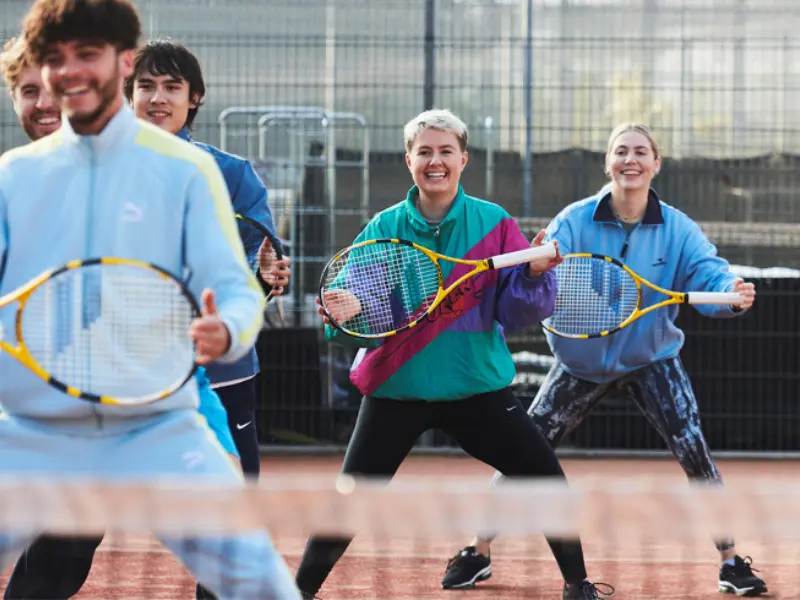Group of coaches holding rackets out in front, doing warm up for cardio tennis