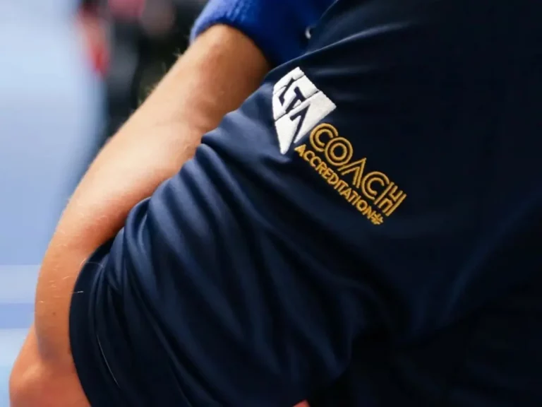 Arm of tennis coach with LTA Coach Accreditation badge on sleeve