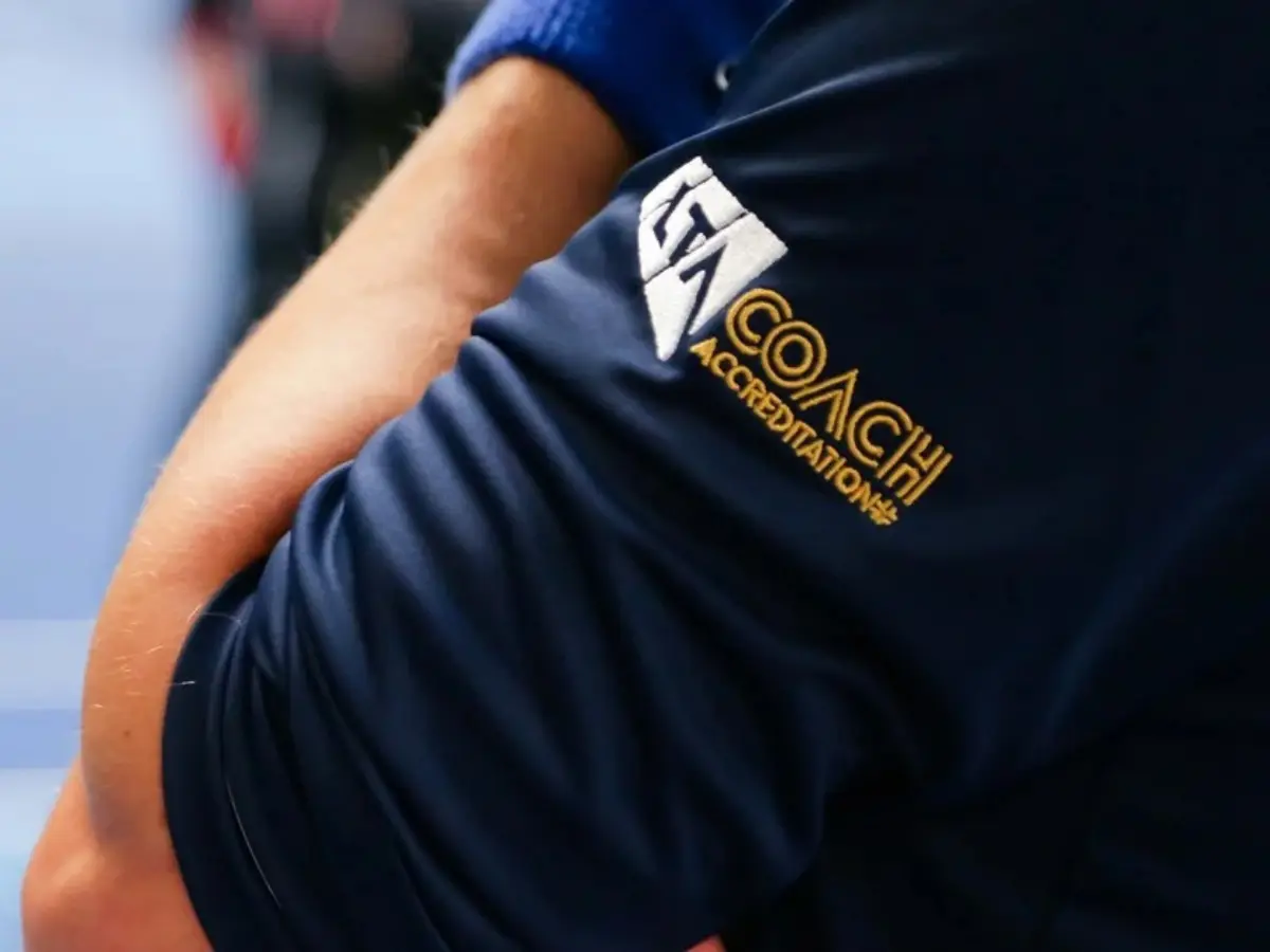 Arm of tennis coach with LTA Coach Accreditation badge on sleeve