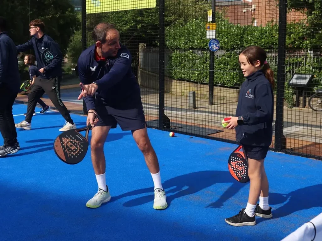Padel coach showing young player where to contact the ball to serve over the net