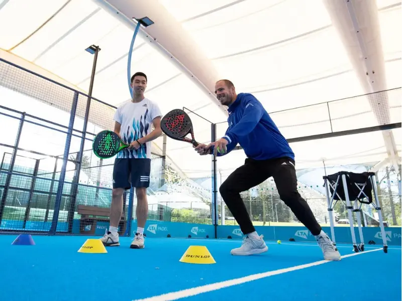 Padel coach showing a player how to hit a forehand volley