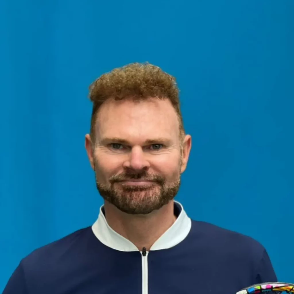 Paul with brown hair, smiling at the camera, with blue jacket, with white collar
