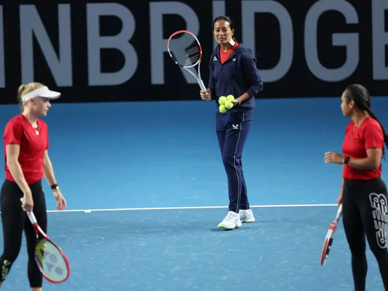 Coach holding tennis racket and 4 balls in hand, ready to feed
