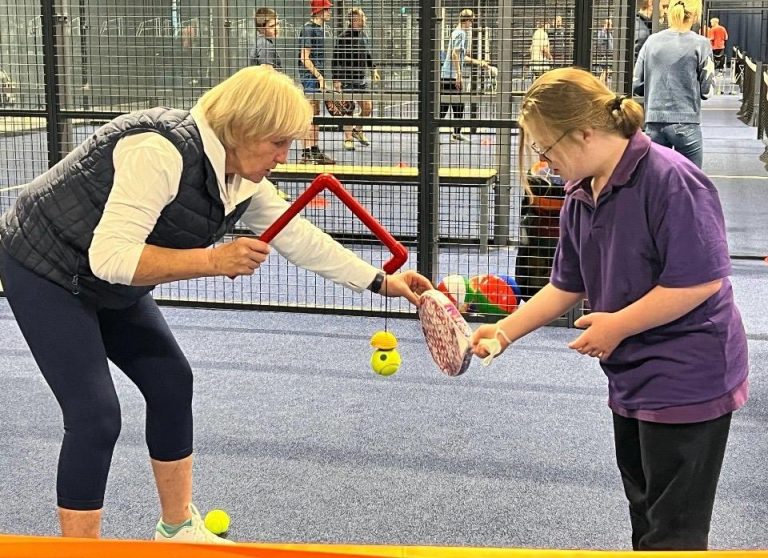 A padel coach coaching a player with disabilities